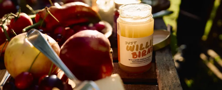 Frisches Obst neben einer Flasche Williams-Christ-Birnen-Likör